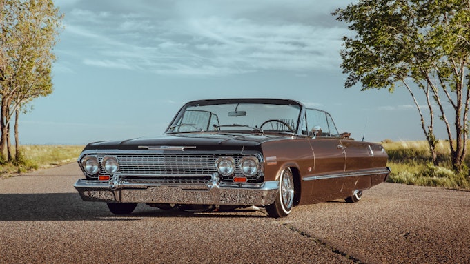 Classic brown Impala convertible parked on the street under autumn trees