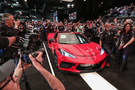 red corvette at auction surrounded by crowd and photographers