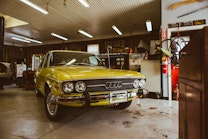 A bright yellow classic Audi is parked inside a workshop.
