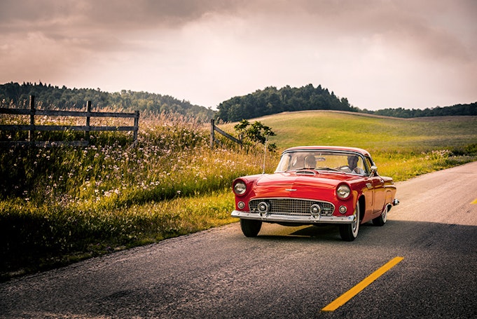 Classic red Thunderbird convertible driving towards us in slight shadow